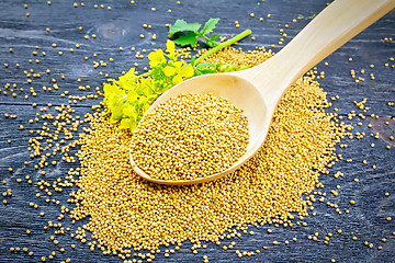 Image showing Mustard seeds in wooden spoon with flower on board