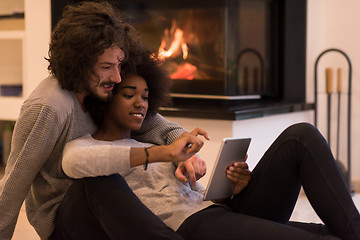 Image showing multiethnic couple using tablet computer on the floor