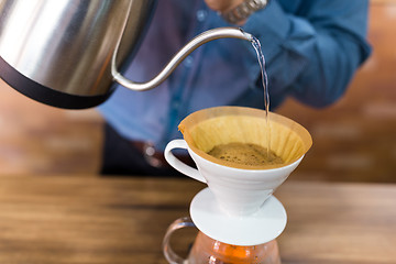 Image showing Barista pouring water on coffee with filter in coffee shop