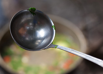 Image showing Wet metal ladle (spoon) with pieces of coriander leaf