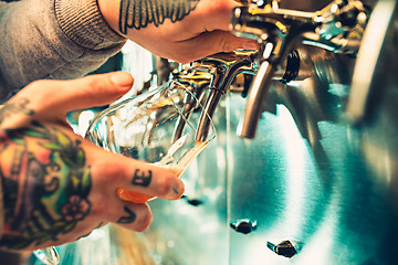 Image showing Hand of bartender pouring a large lager beer in tap.