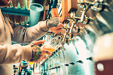 Image showing Hand of bartender pouring a large lager beer in tap.