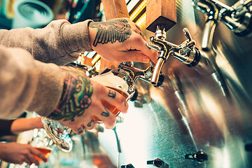 Image showing Hand of bartender pouring a large lager beer in tap.