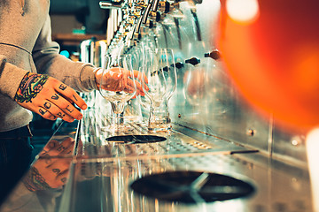 Image showing Hand of bartender pouring a large lager beer in tap.