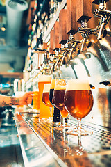 Image showing Hand of bartender pouring a large lager beer in tap.