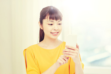 Image showing happy asian woman with smartphone at home