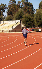 Image showing Older man running on curve at track