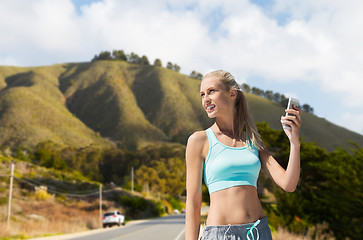 Image showing woman with smartphone doing sports over hills