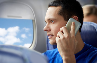 Image showing young man calling on smartphone in plane