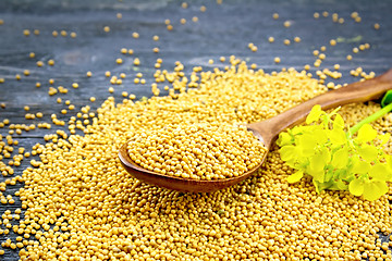 Image showing Mustard seeds in spoon with flower on black board