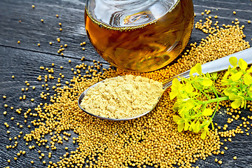 Image showing Mustard powder in spoon with oil and flower on black board