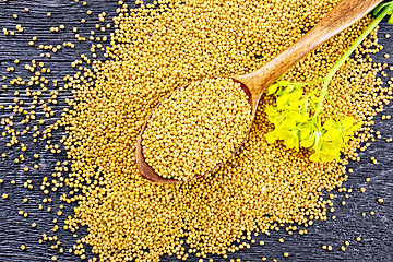 Image showing Mustard seeds in spoon with flower on board top