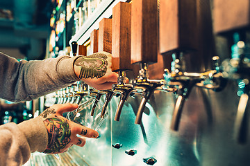 Image showing Hand of bartender pouring a large lager beer in tap.