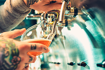 Image showing Hand of bartender pouring a large lager beer in tap.