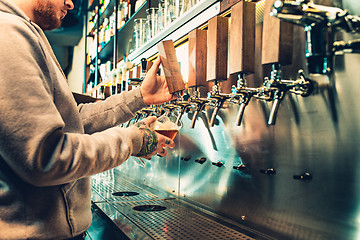 Image showing Hand of bartender pouring a large lager beer in tap.