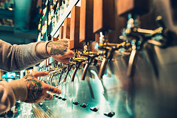 Image showing Hand of bartender pouring a large lager beer in tap.