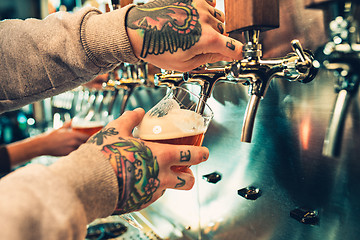 Image showing Hand of bartender pouring a large lager beer in tap.