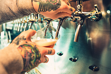 Image showing Hand of bartender pouring a large lager beer in tap.