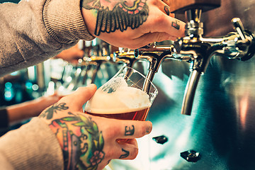 Image showing Hand of bartender pouring a large lager beer in tap.