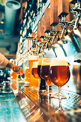 Image showing Hand of bartender pouring a large lager beer in tap.