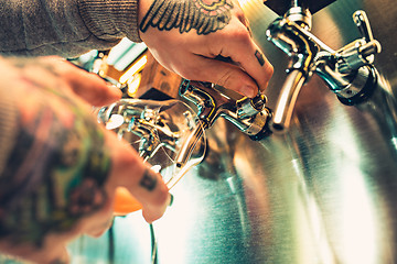 Image showing Hand of bartender pouring a large lager beer in tap.