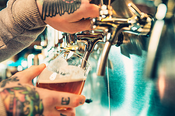 Image showing Hand of bartender pouring a large lager beer in tap.