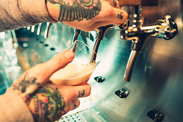 Image showing Hand of bartender pouring a large lager beer in tap.