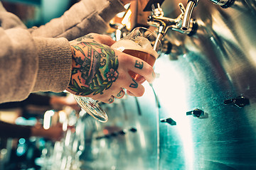 Image showing Hand of bartender pouring a large lager beer in tap.