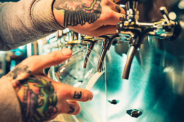 Image showing Hand of bartender pouring a large lager beer in tap.