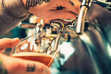 Image showing Hand of bartender pouring a large lager beer in tap.