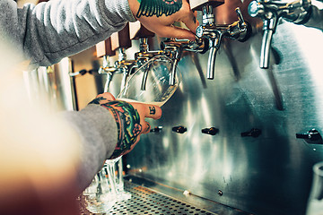 Image showing Hand of bartender pouring a large lager beer in tap.