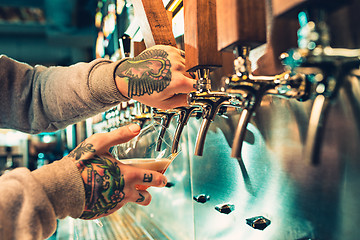 Image showing Hand of bartender pouring a large lager beer in tap.