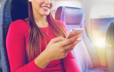 Image showing close up of woman sitting in plane with smartphone