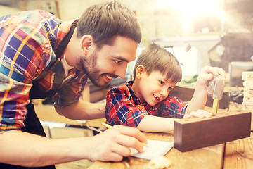 Image showing dad and son with ruler measuring plank at workshop