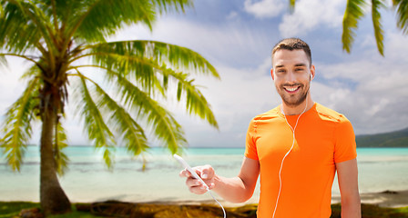 Image showing man with smartphone and earphones over beach