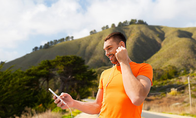 Image showing man with smartphone and earphones over hills