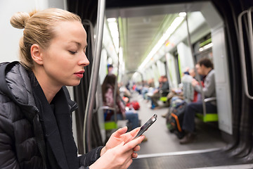 Image showing Young girl reading from mobile phone screen in metro.