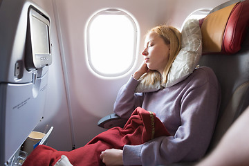 Image showing Tired blonde casual caucasian lady sleepin on seat while traveling by airplane. Commercial transportation by planes.