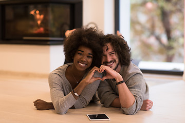 Image showing multiethnic couple showing a heart with their hands on the floor