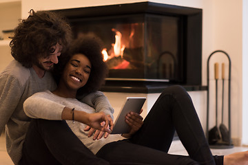 Image showing multiethnic couple using tablet computer on the floor