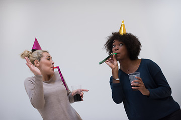 Image showing smiling women in party caps blowing to whistles