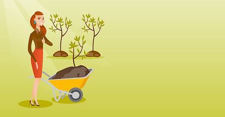 Image showing Woman pushing wheelbarrow with plant.