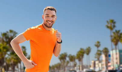 Image showing smiling young man running at summer seaside