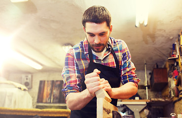 Image showing carpenter working with plane and wood at workshop