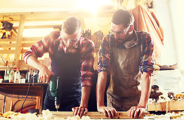 Image showing carpenters with drill drilling plank at workshop