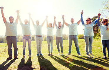 Image showing group of happy volunteers holding hands outdoors