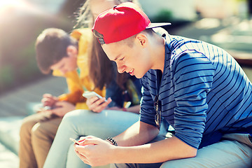 Image showing happy teenage friends with smartphones outdoors