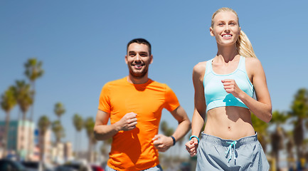 Image showing smiling couple jogging at summer over venice beach