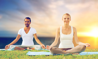 Image showing happy couple making yoga and meditating outdoors