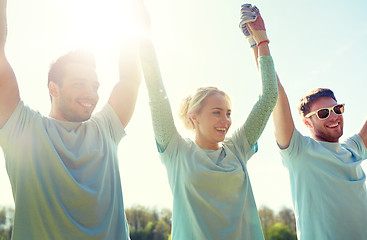 Image showing group of happy volunteers holding hands outdoors